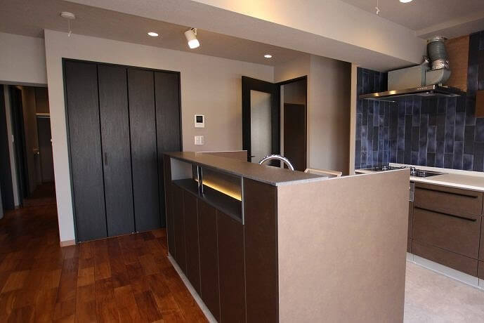 青いタイルにグレージュのカウンターキッチンが落ち着いた印象をあたえる